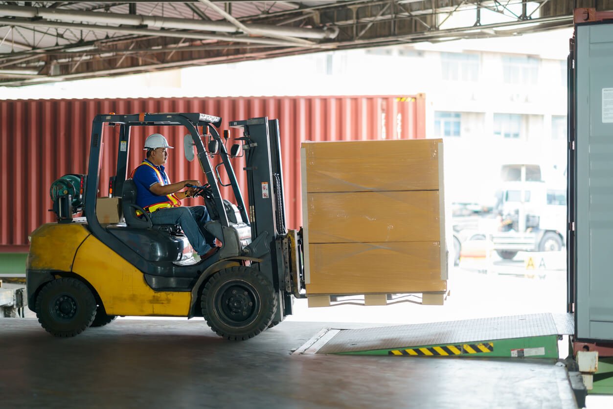 man operating forklift and carrying a load to weigh on a scale